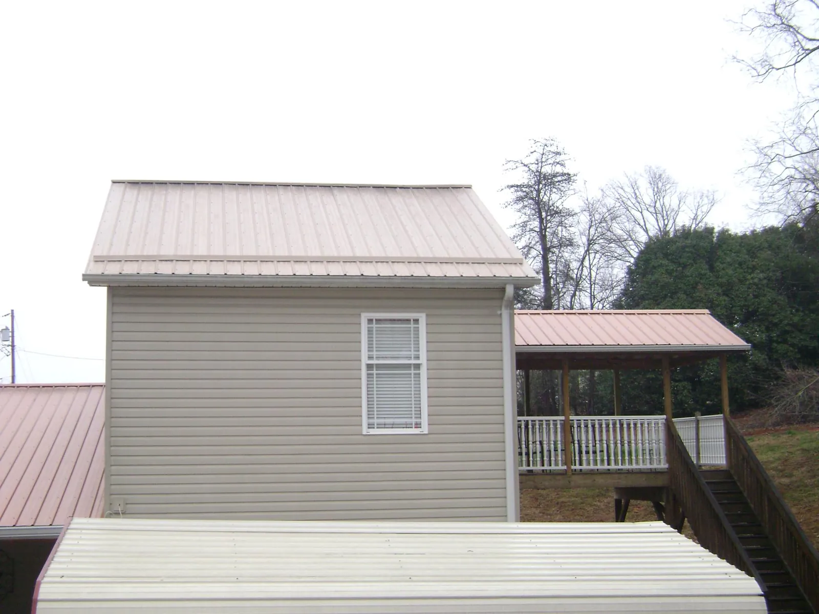 Tan metal roofs on a two story addition and attached porch, from a Roof Replacement job in Wilsonville