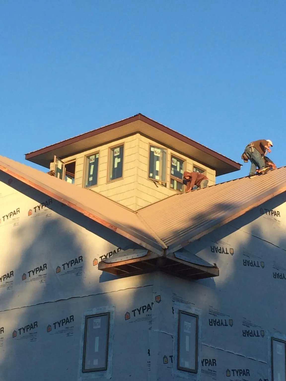 Roofers working around a rooftop cupola on a new metal roof at sunset — Roof Waterproofing in Wilsonville by Roofing Brothers